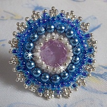 Bague Azur brodée avec un cabochon en Cristal de couleur Antique Pink à laquelle s'ajoute des rocailles et perles rondes nacrées. Le tout est monté sur une bague filigranée Blanche